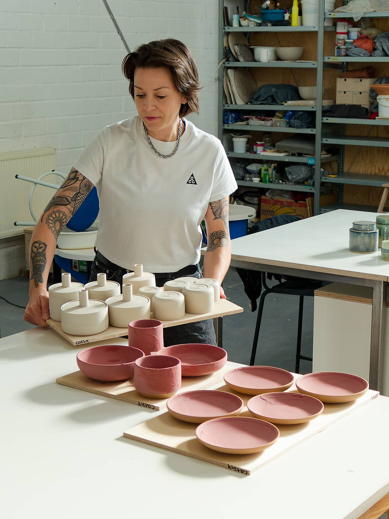 Cathy Daniels arranging unglazed ceramic tableware on boards in her Berlin studio.