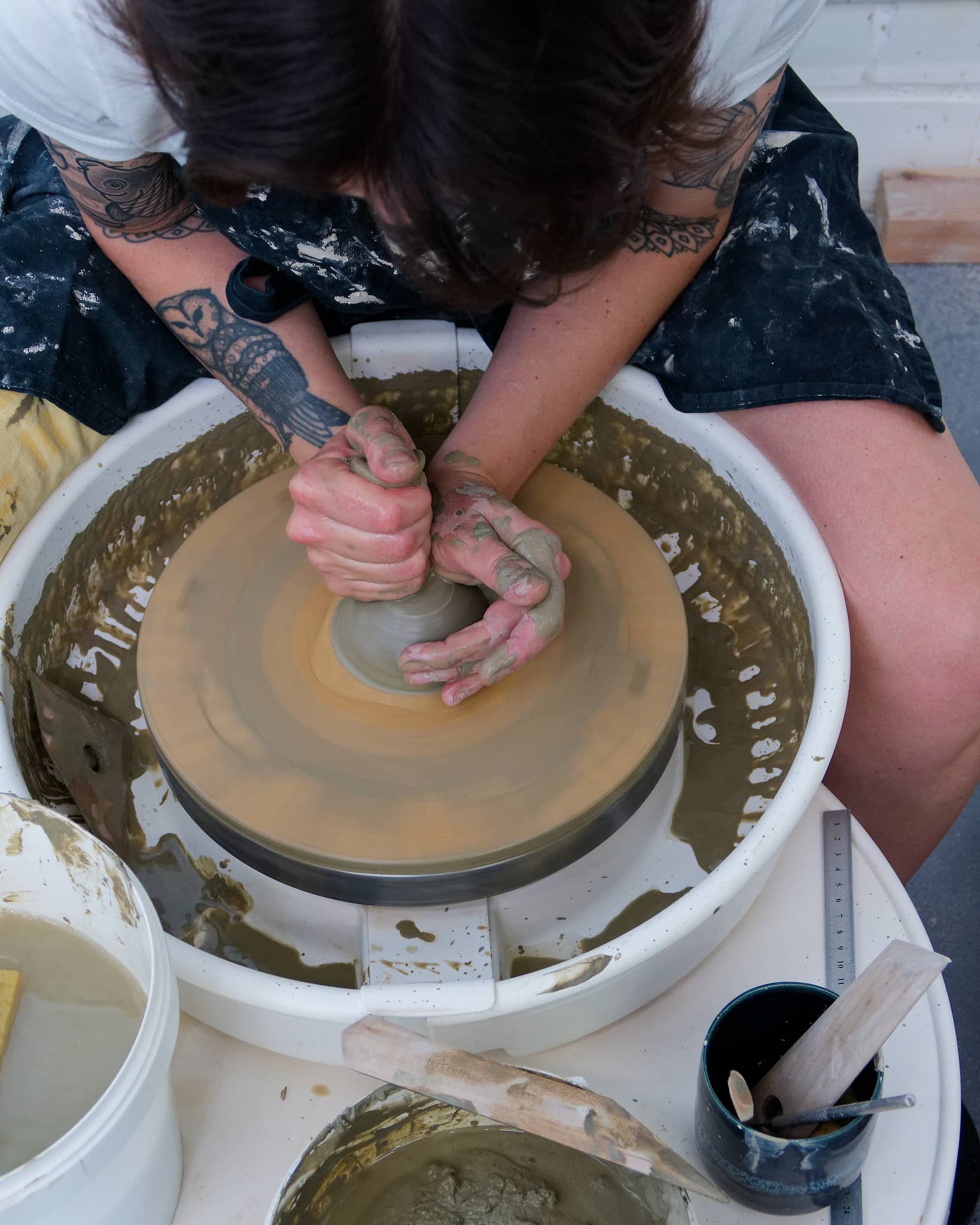 Overhead view of Cathy Daniels centering clay on a spinning pottery wheel.